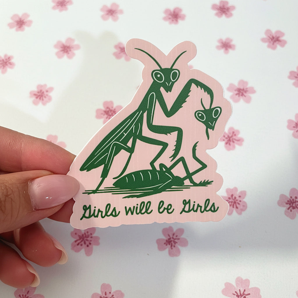 Sticker with green praying mantis illustration and 'Girls will be girls' text on pink background, held by a hand.