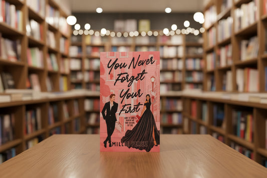 Book titled 'You Never Forget Your First' by Millie Perez on a pink textured  surface with a light blue background.