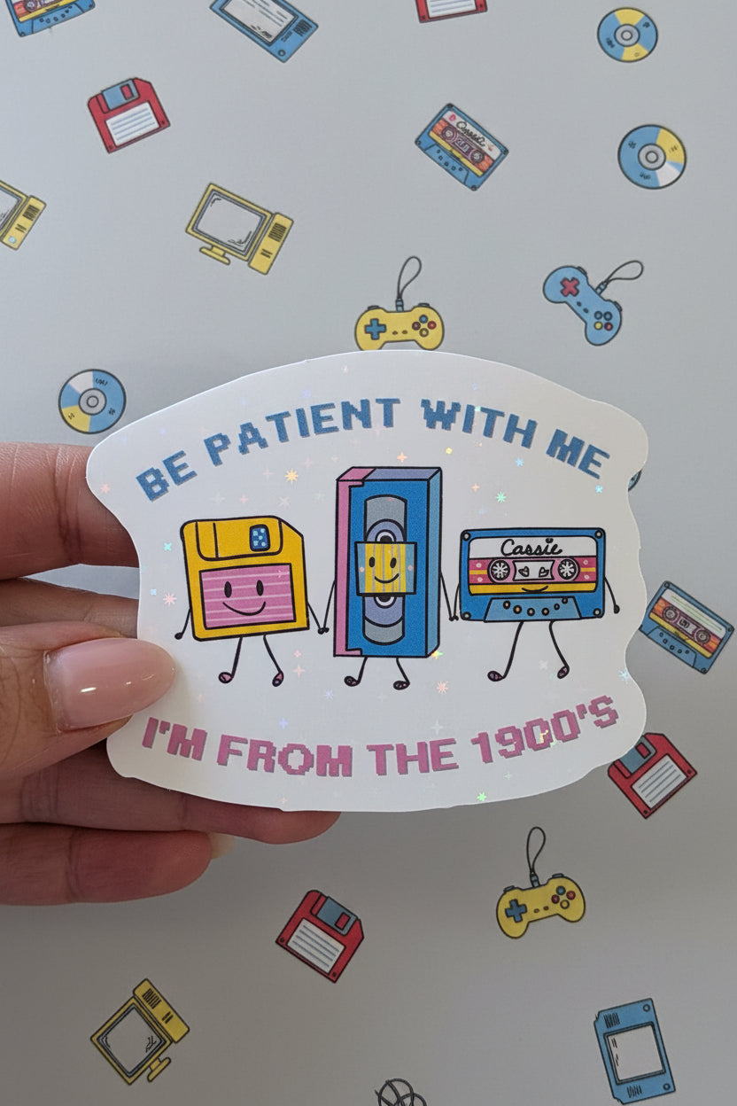 Hand holding a sticker with retro television designs and text on a pink background