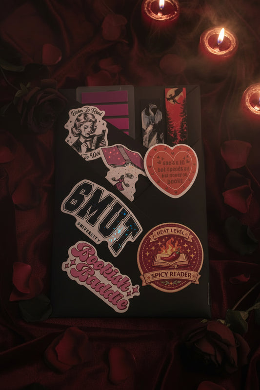 Book wrapped in black craft paper with various stickers and bookmarks for a dark romance vibe